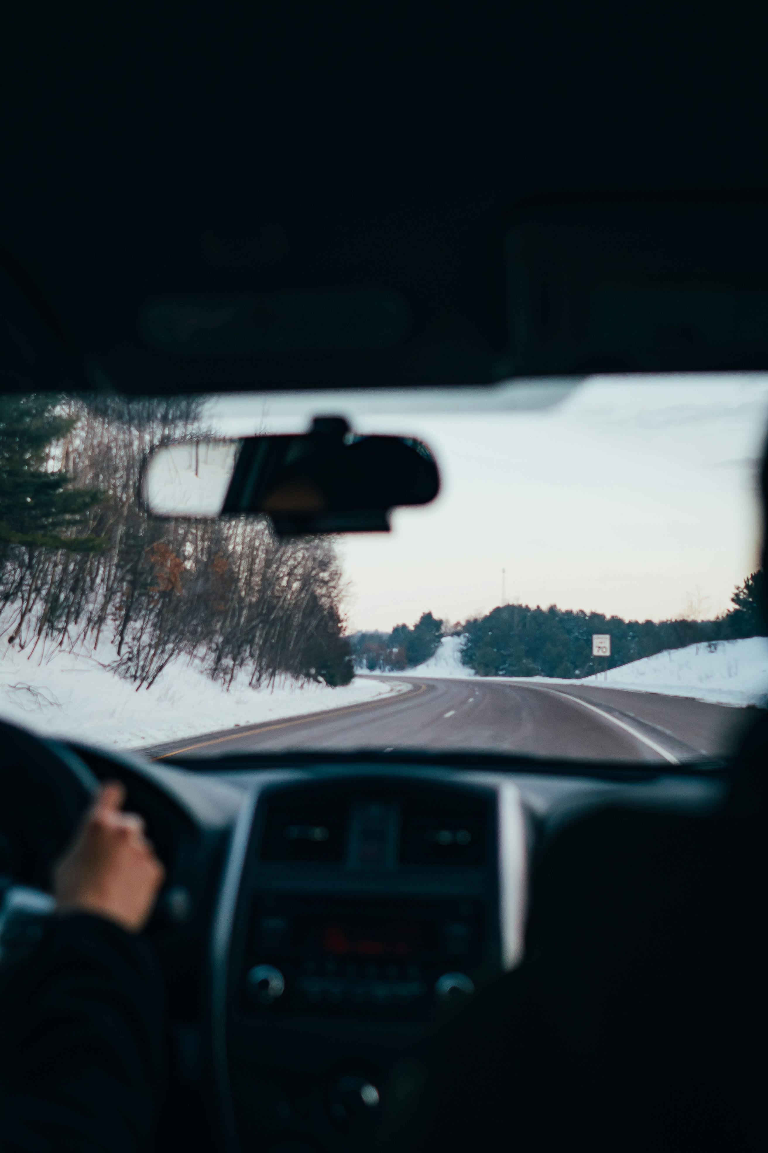 Driving along a snowy highway in winter, capturing the serene landscape and vehicle interior view.